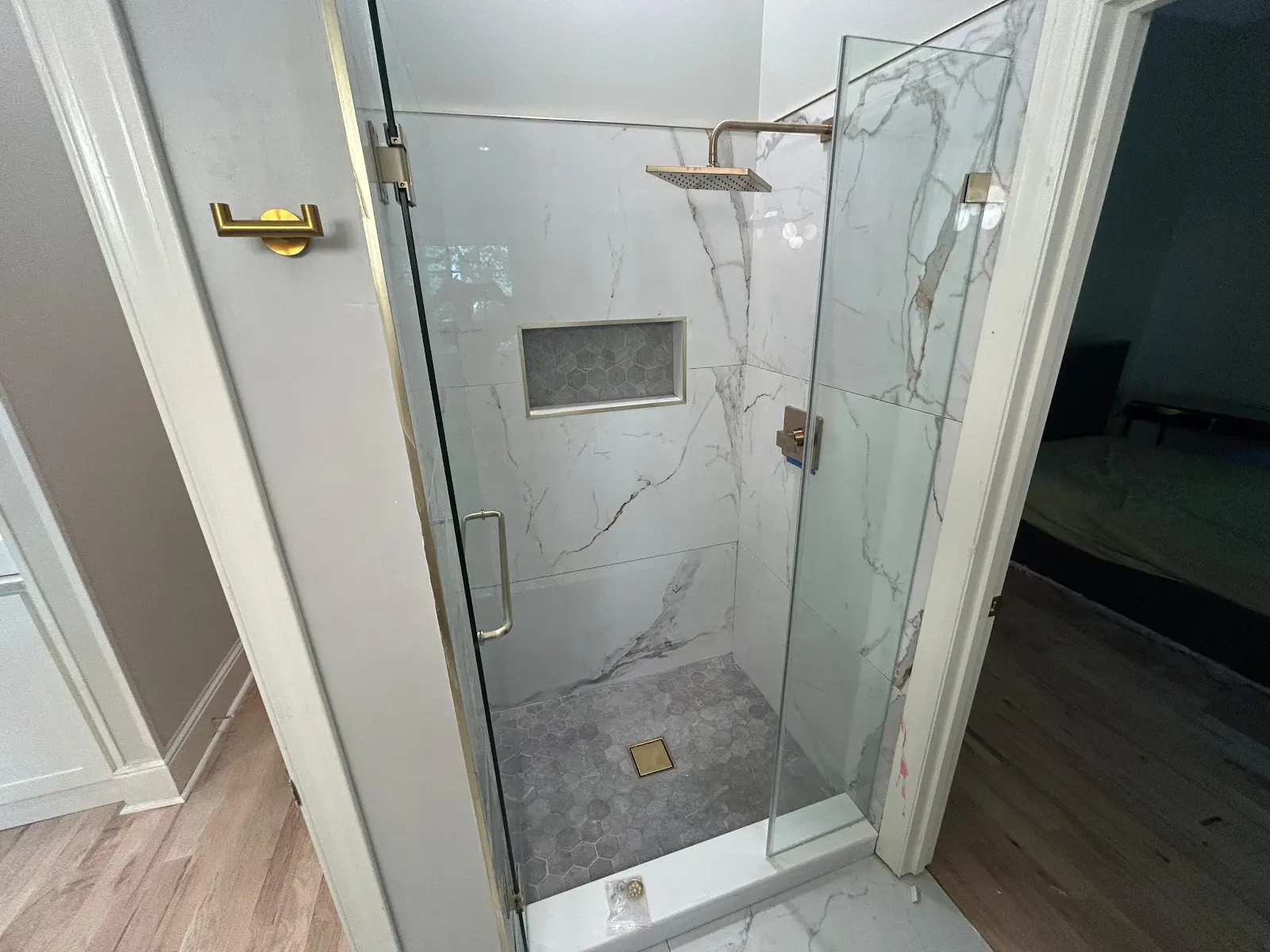 Completed walk-in shower with marble-look tile and frameless glass door